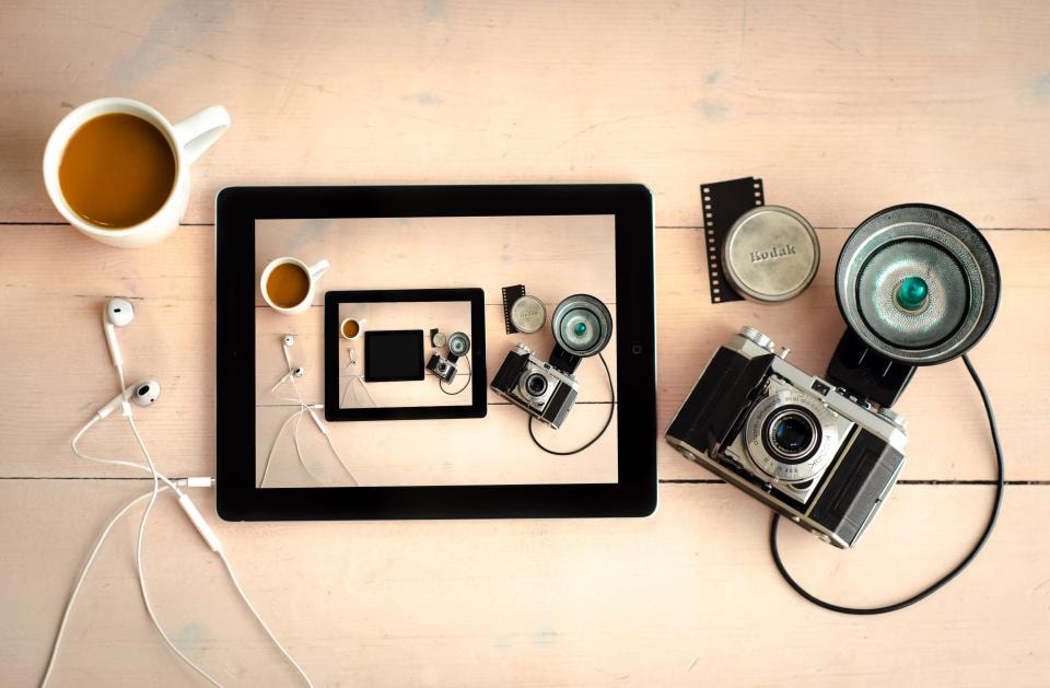 A desk with a tablet, cameras, a cup and earphones, each object segmented
