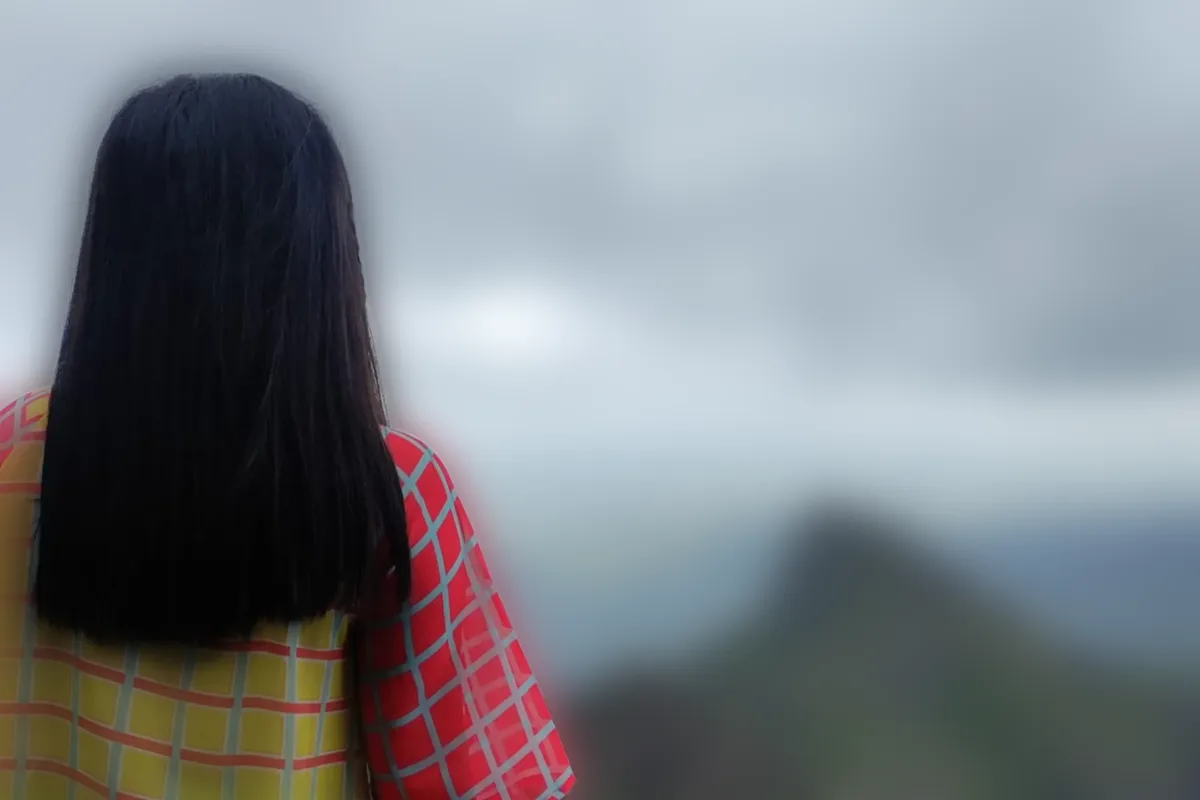 A woman on a mountain top, the valley behind her softly blurred