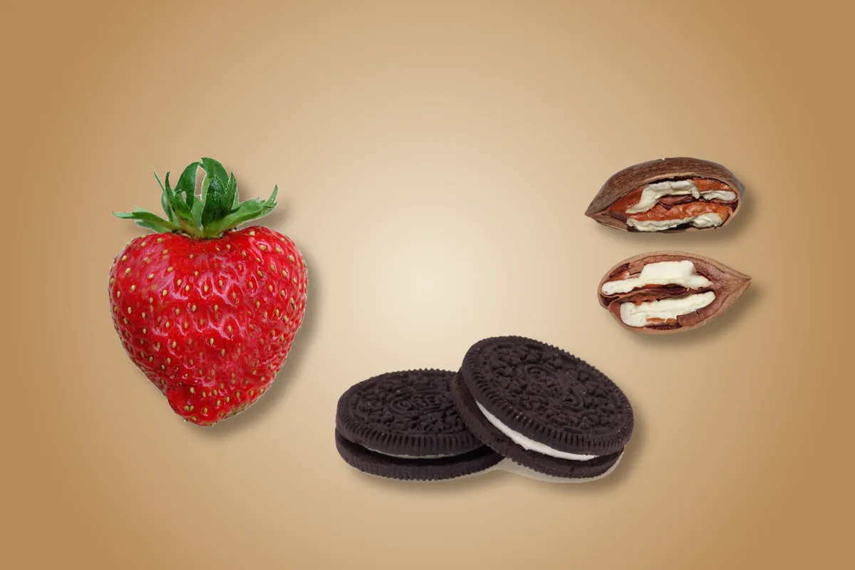 A table with a strawberry, two biscuits and two pecans on it