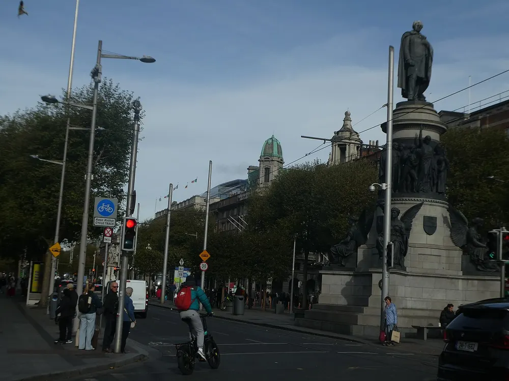 A city street with a cyclist, pedestrians, a traffic light and a car, with objects outlined for labelling