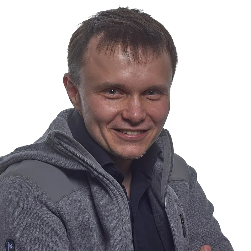 A smiling man in front of a light grey background