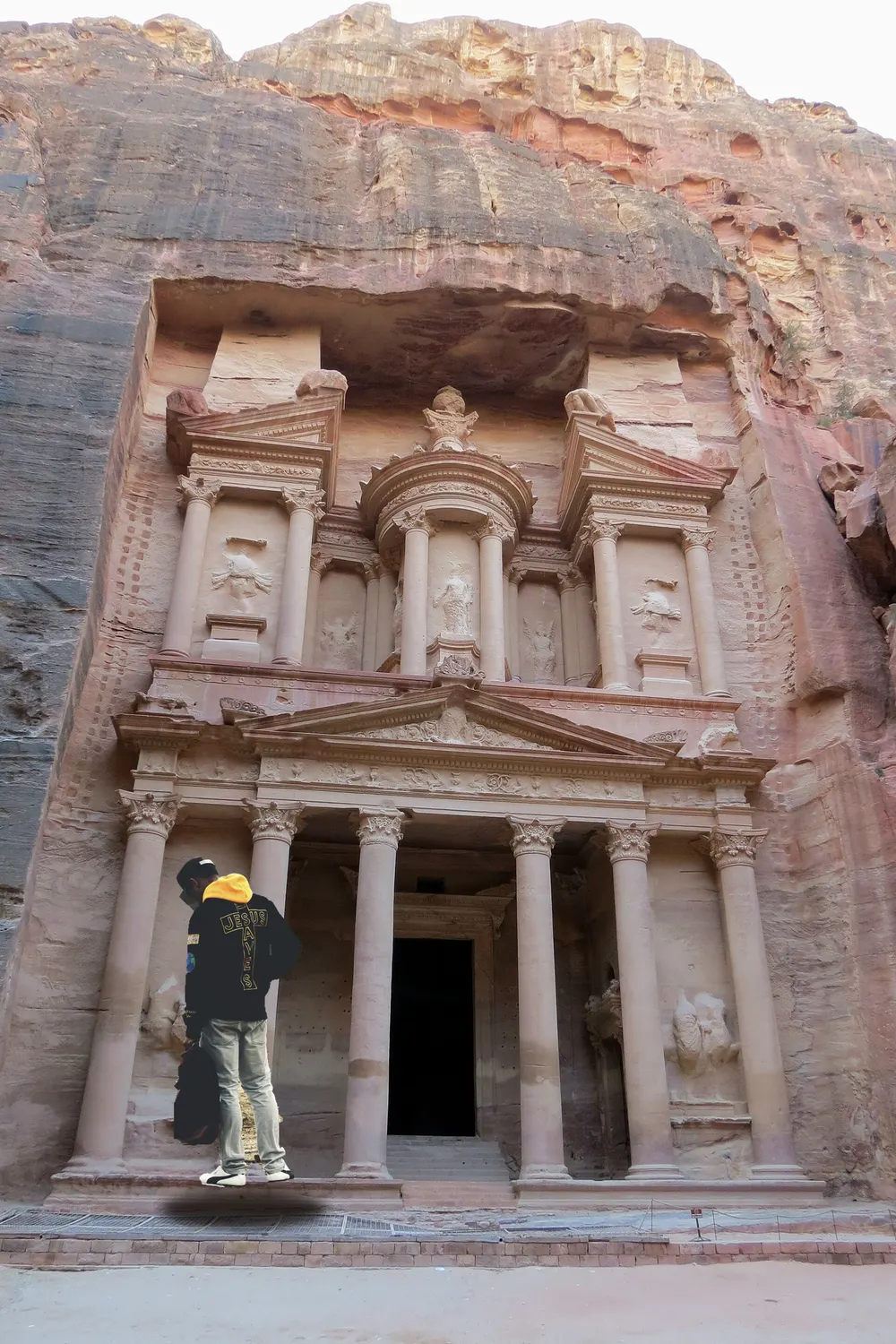 A sandstone temple facade with a visitor standing in front of it
